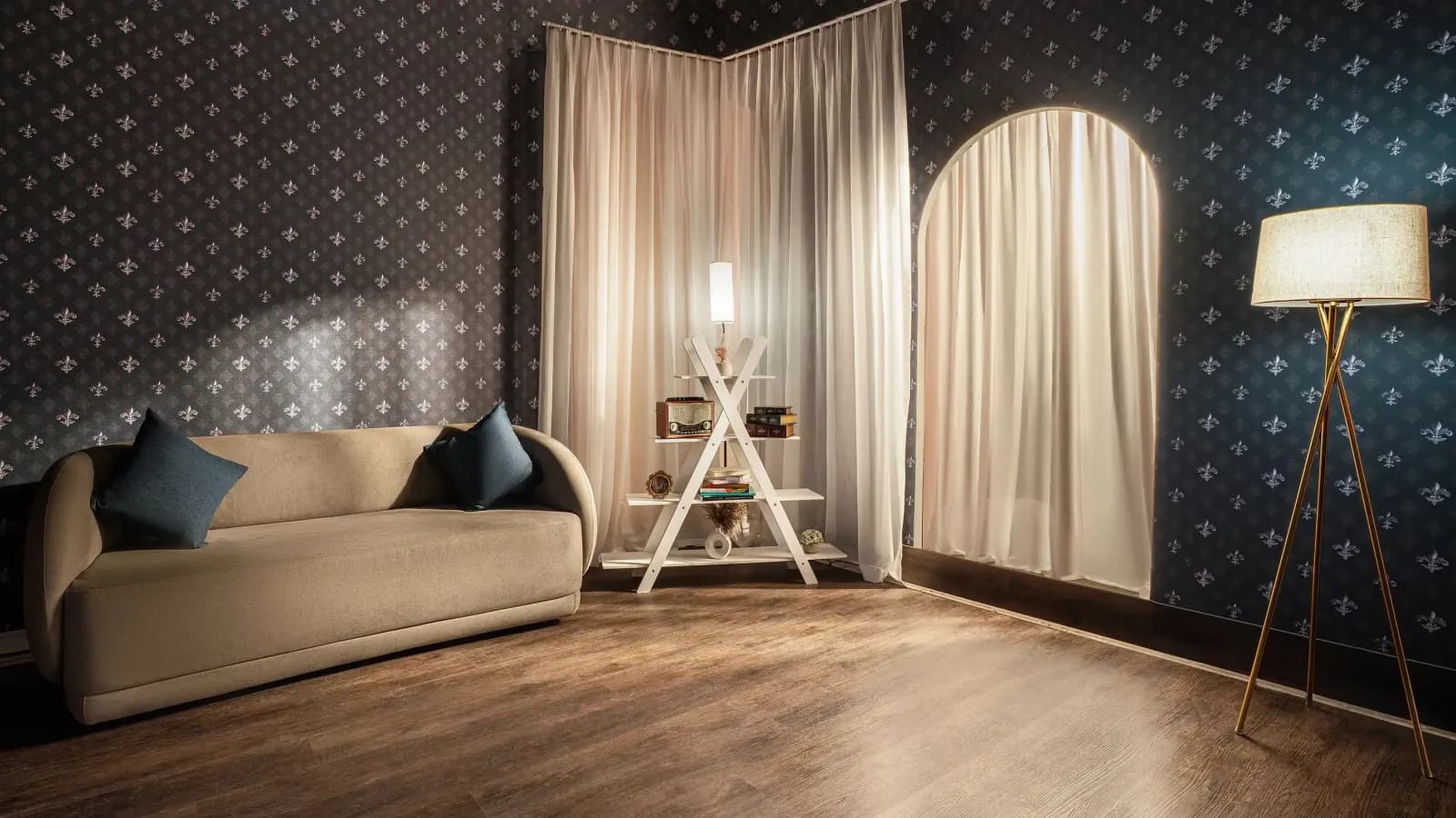 A room with fleur-de-lis walls, a sofa and an arched, curtained window